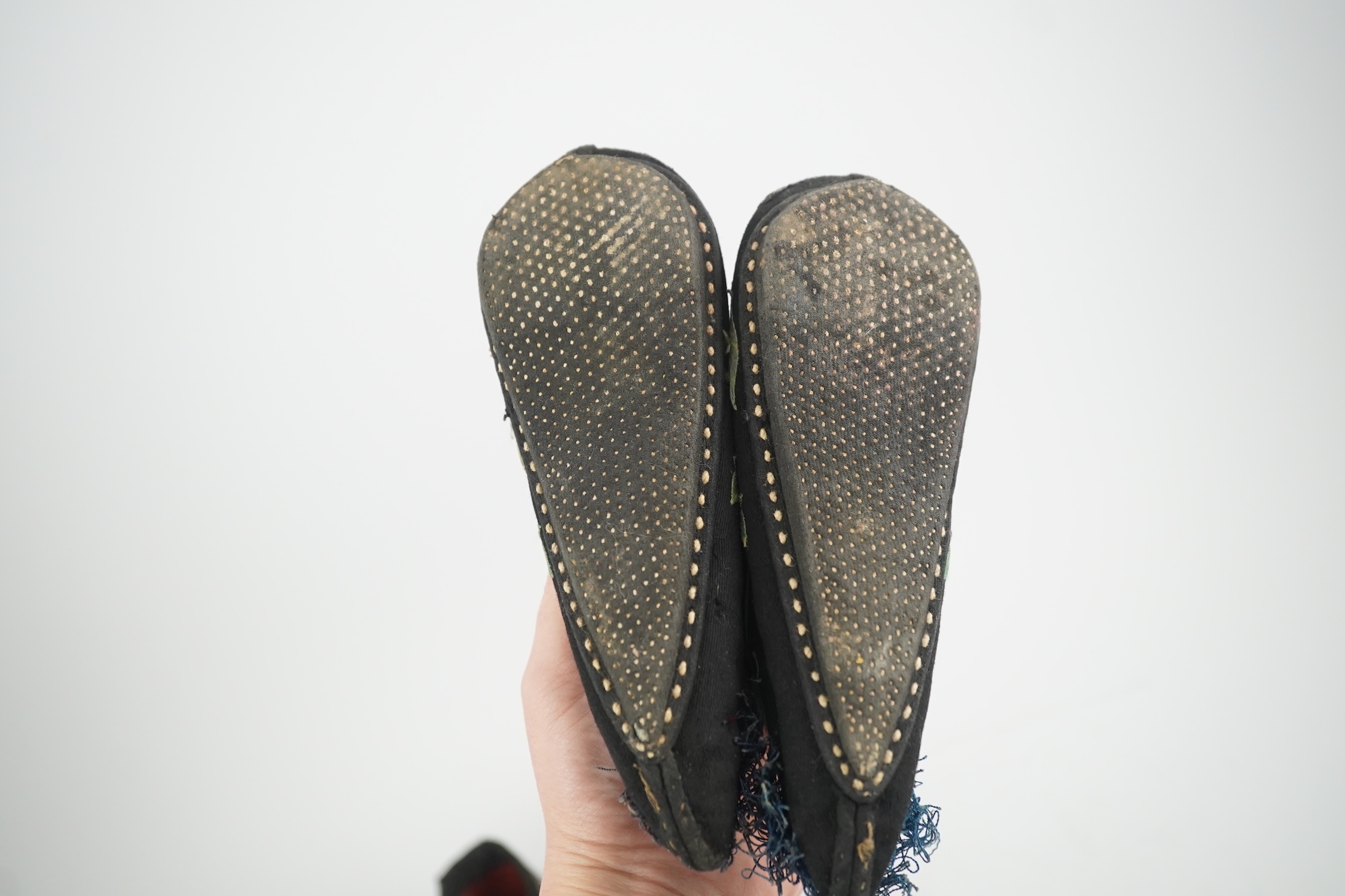 Four pairs of late 19th / early 20th Chinese ladies bound foot shoes, made in various coloured silks, with colourful floral embroidered motifs, two pairs with decorative silk pom-poms and another made of purple and black